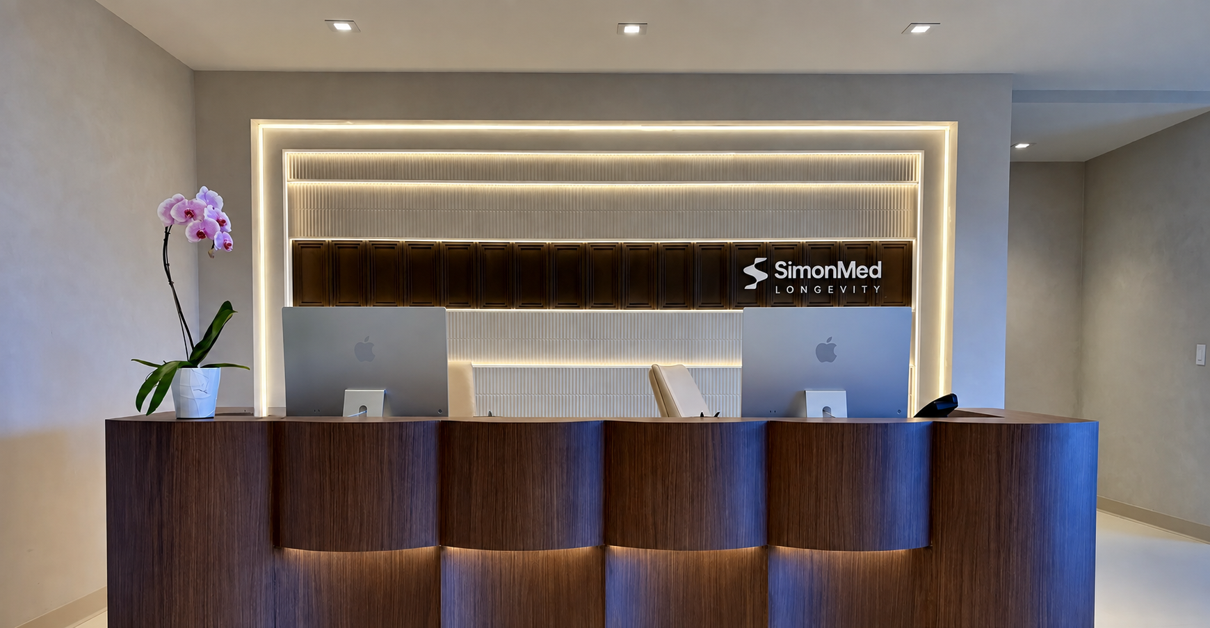 SimonMed Longevity reception with wood desk and illuminated wall